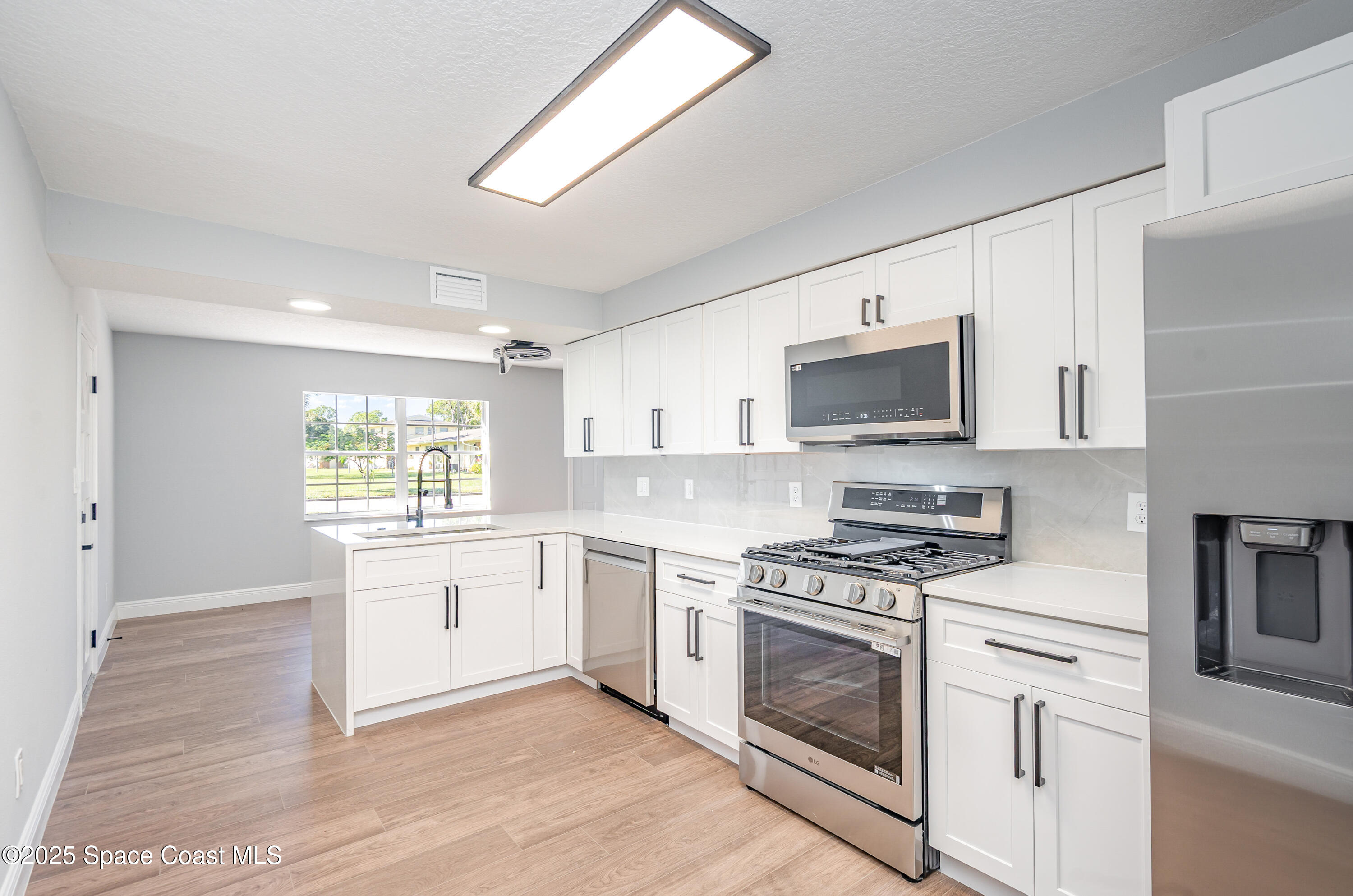 1735 Marywood Road Melbourne, FL 32934 - Photo 9 of 25 a kitchen with white cabinets stainless steel appliances and sink