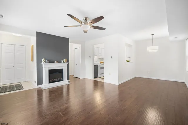 a view of an empty room with wooden floor and a fireplace