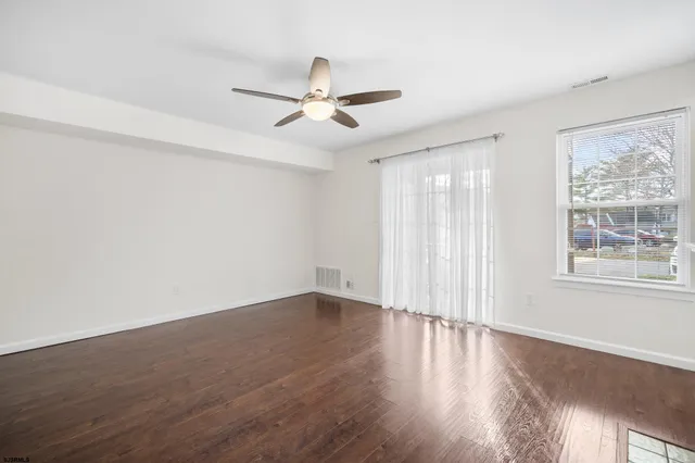 an empty room with wooden floor fan and windows