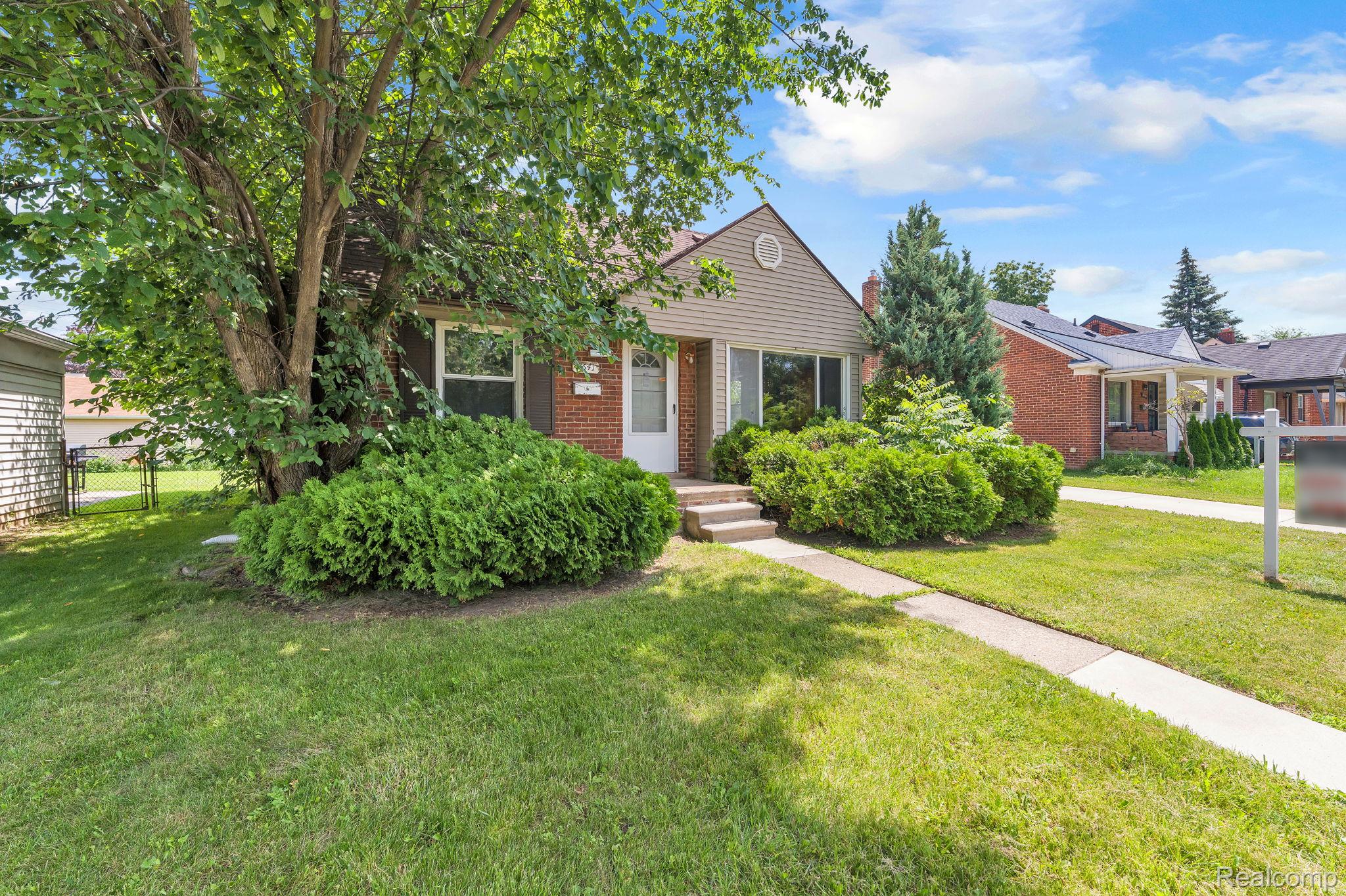 7641 Pelham Road Allen Park, MI 48101 - Photo 3 of 21 Exterior featuring a gabled roofline, siding, brick accents, a mature tree, and established shrubbery
