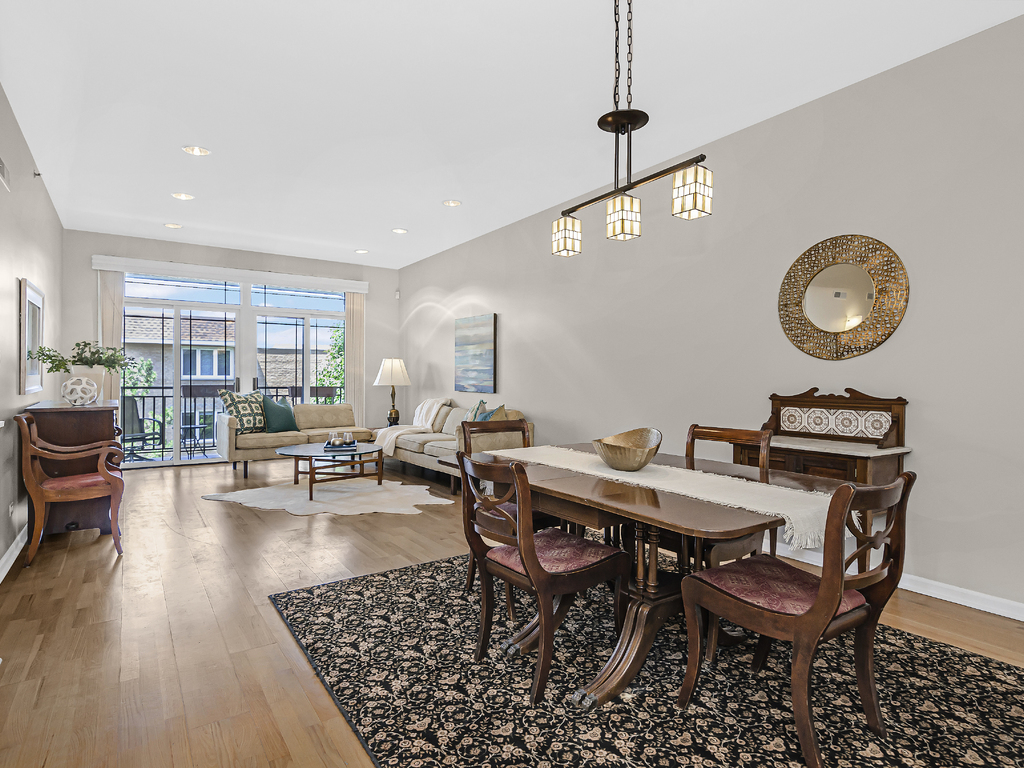 9200 East Prairie Road, Unit 403 Evanston, IL 60203 - Photo 5 of 23 a view of a dining room and livingroom with furniture wooden floor a rug and a clock