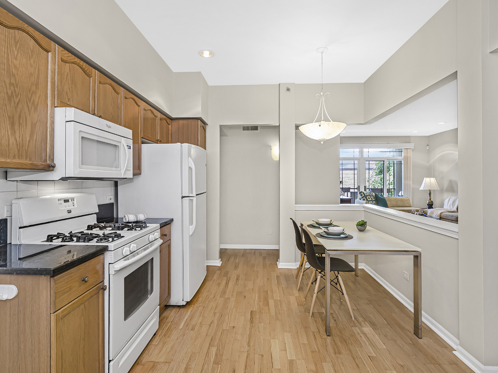 9200 East Prairie Road, Unit 403 Evanston, IL 60203 - Photo 9 of 23 a kitchen with stainless steel appliances a stove a sink dishwasher a refrigerator white cabinets and wooden floor