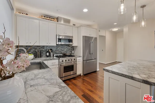a kitchen with stainless steel appliances granite countertop a stove a sink and a refrigerator