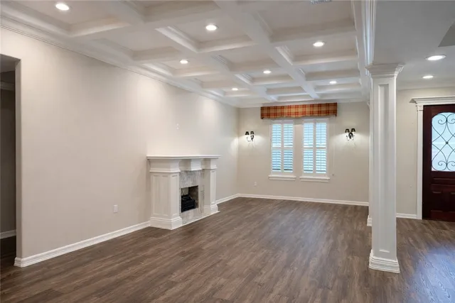 a view of an empty room with wooden floor and a kitchen