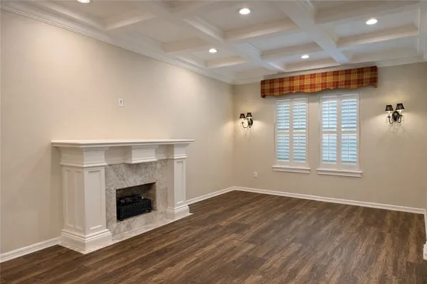 a view of an empty room with wooden floor fireplace and a window