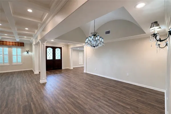 a view of an empty room with wooden floor and a kitchen