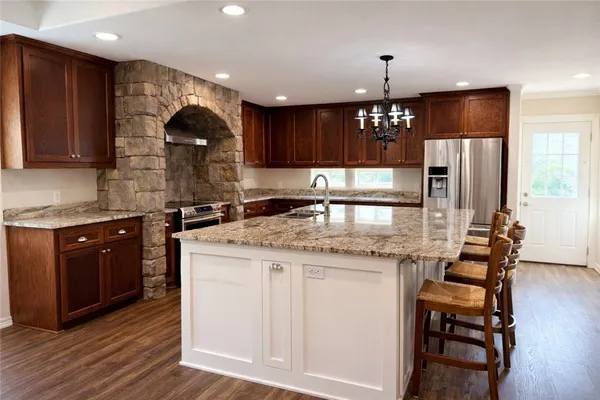 a kitchen with kitchen island granite countertop wooden cabinets and a refrigerator