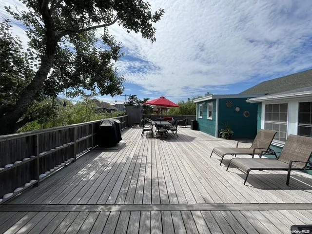 a view of a roof deck with table and chairs with wooden floor and fence