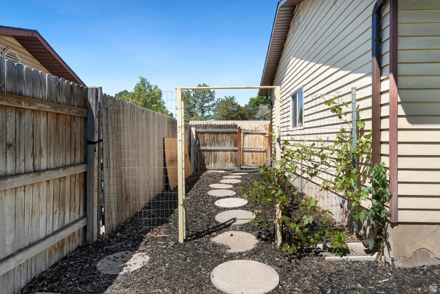 865 South 325 West Orem, UT 84058 - Photo 32 of 38 Side yard with a wood picket fence, round stepping stones, and a bark mulch ground cover