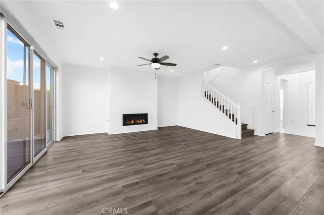 a kitchen with stainless steel appliances kitchen island granite countertop a stove a sink a refrigerator white cabinets and wooden floor