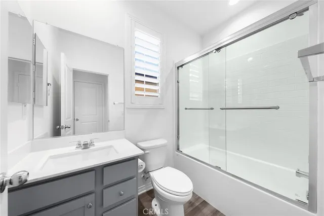 an empty room with wooden floor a ceiling fan and windows