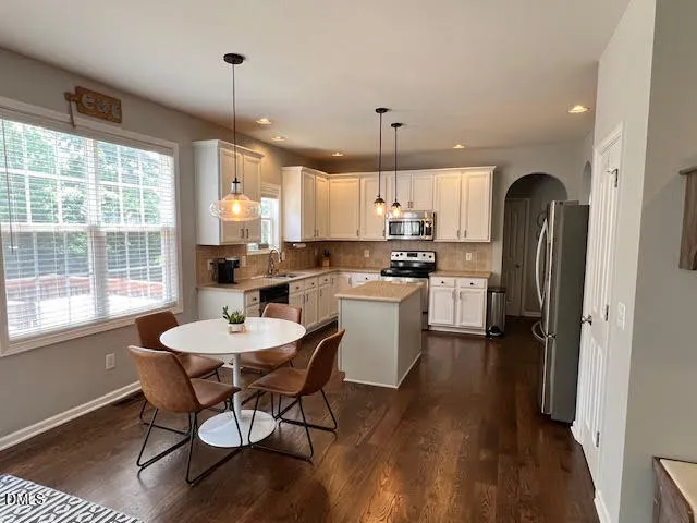 a kitchen with a dining table chairs stainless steel appliances and cabinets