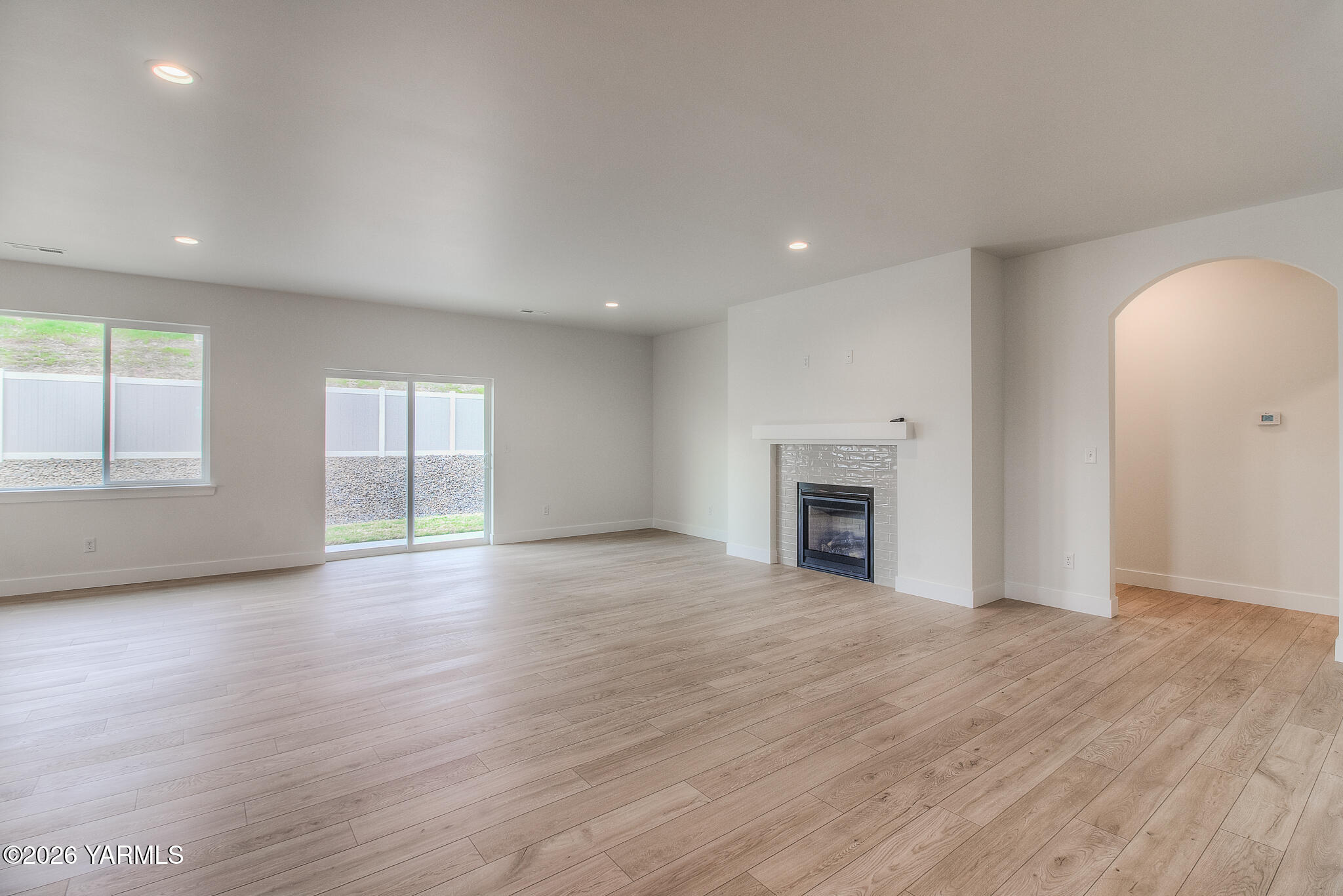 404 South 90th Avenue Yakima, WA 98908 - Photo 6 of 20 an empty room with wooden floor fireplace and windows
