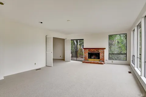 an empty room with a fireplace and a floor to ceiling window