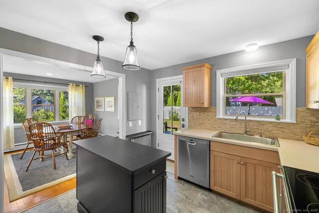 a kitchen with a stove a sink a dining table and chairs with wooden floor