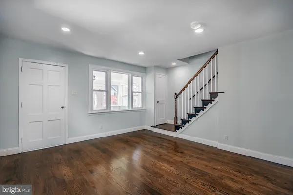 a view of an empty room with wooden floor and stairs
