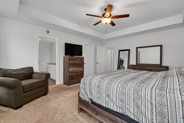 a bedroom with a bed couch and ceiling fan