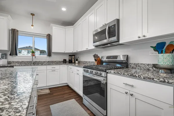 a kitchen with stainless steel appliances granite countertop a stove a sink and a microwave
