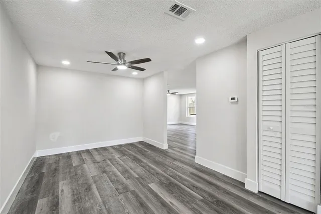 a view of a hallway with wooden floor and a bathroom