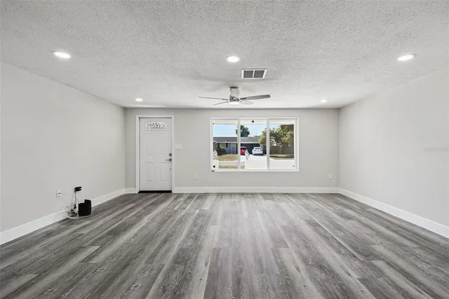a kitchen with a refrigerator and white cabinets with wooden floor
