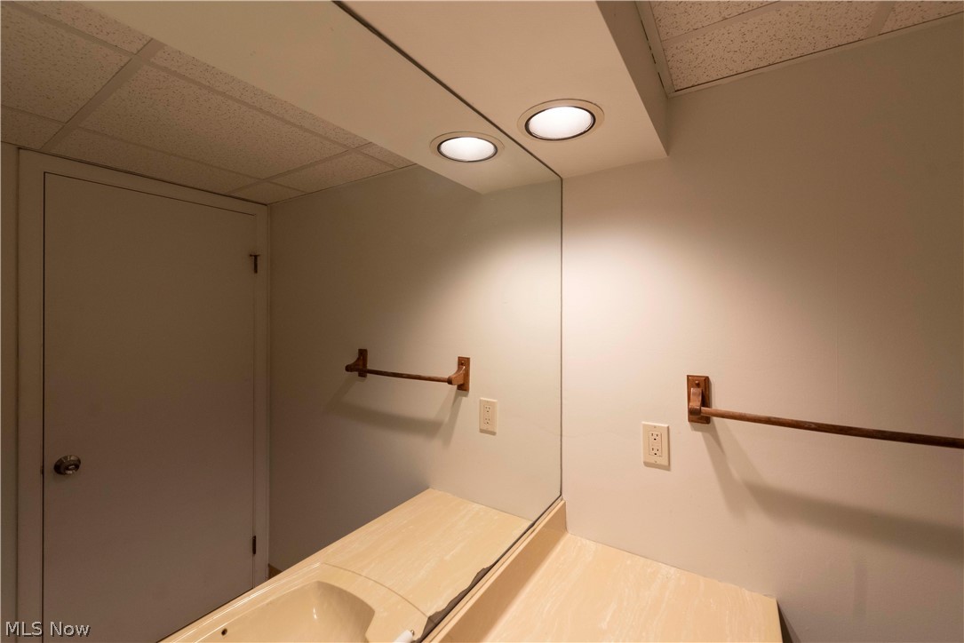 400 Baldwin Road Akron, OH 44312 - Photo 26 of 43 Super helpful half bath in basement featuring a built-in countertop with an integrated sink, large wall-mounted mirror, and recessed overhead lighting