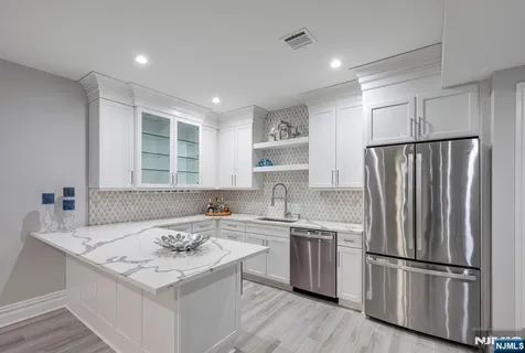 a kitchen that has a sink a refrigerator a window and white cabinets
