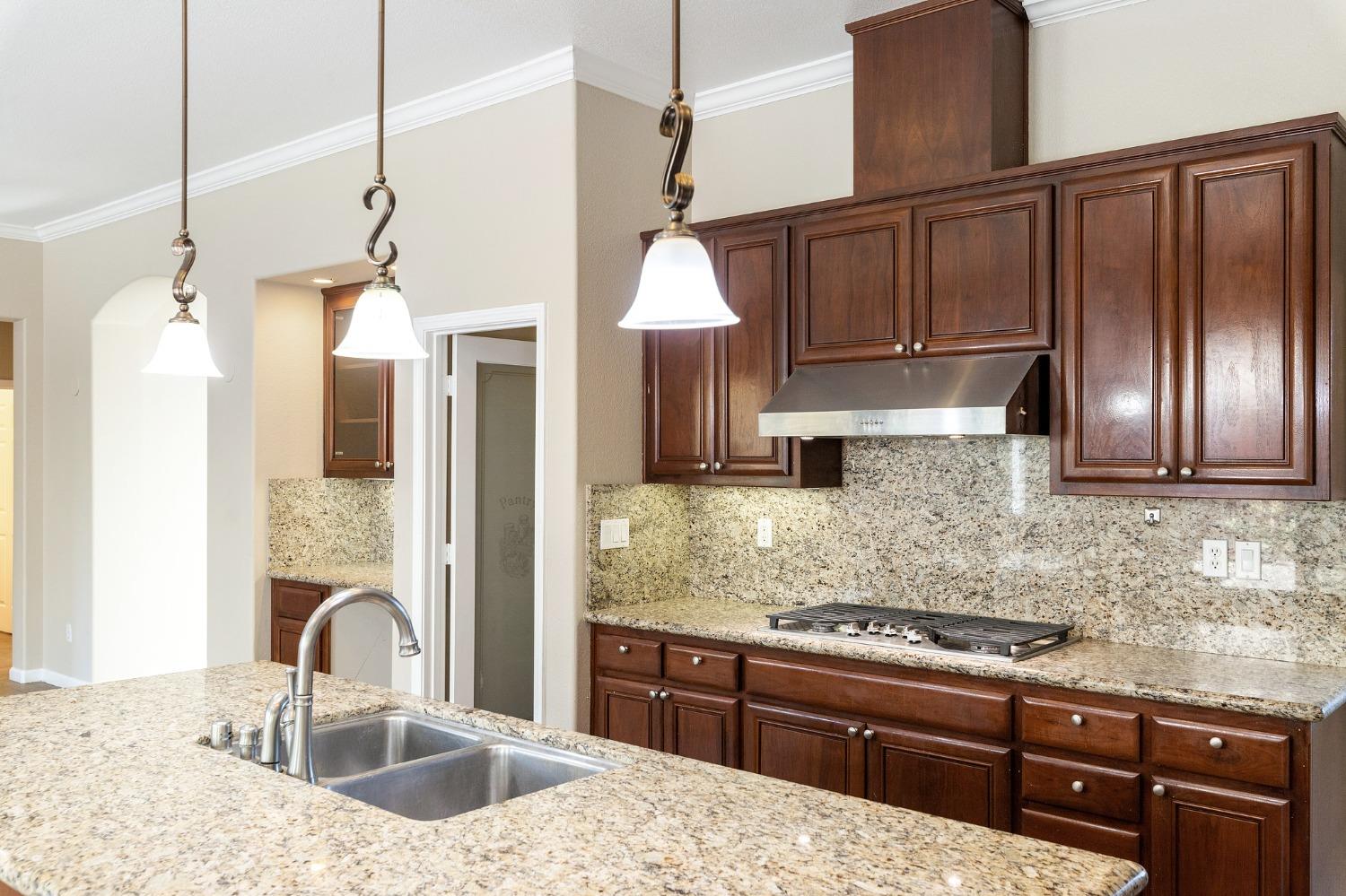 2090 Wisteria Place Manteca, CA 95337 - Photo 20 of 78 a kitchen with kitchen island granite countertop a sink stainless steel appliances and cabinets