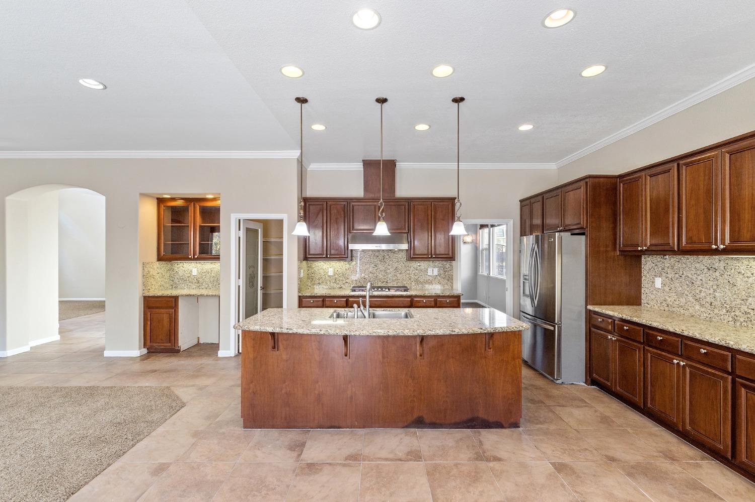 2090 Wisteria Place Manteca, CA 95337 - Photo 21 of 78 a large kitchen with stainless steel appliances kitchen island granite countertop a stove a refrigerator a oven and a view of living room