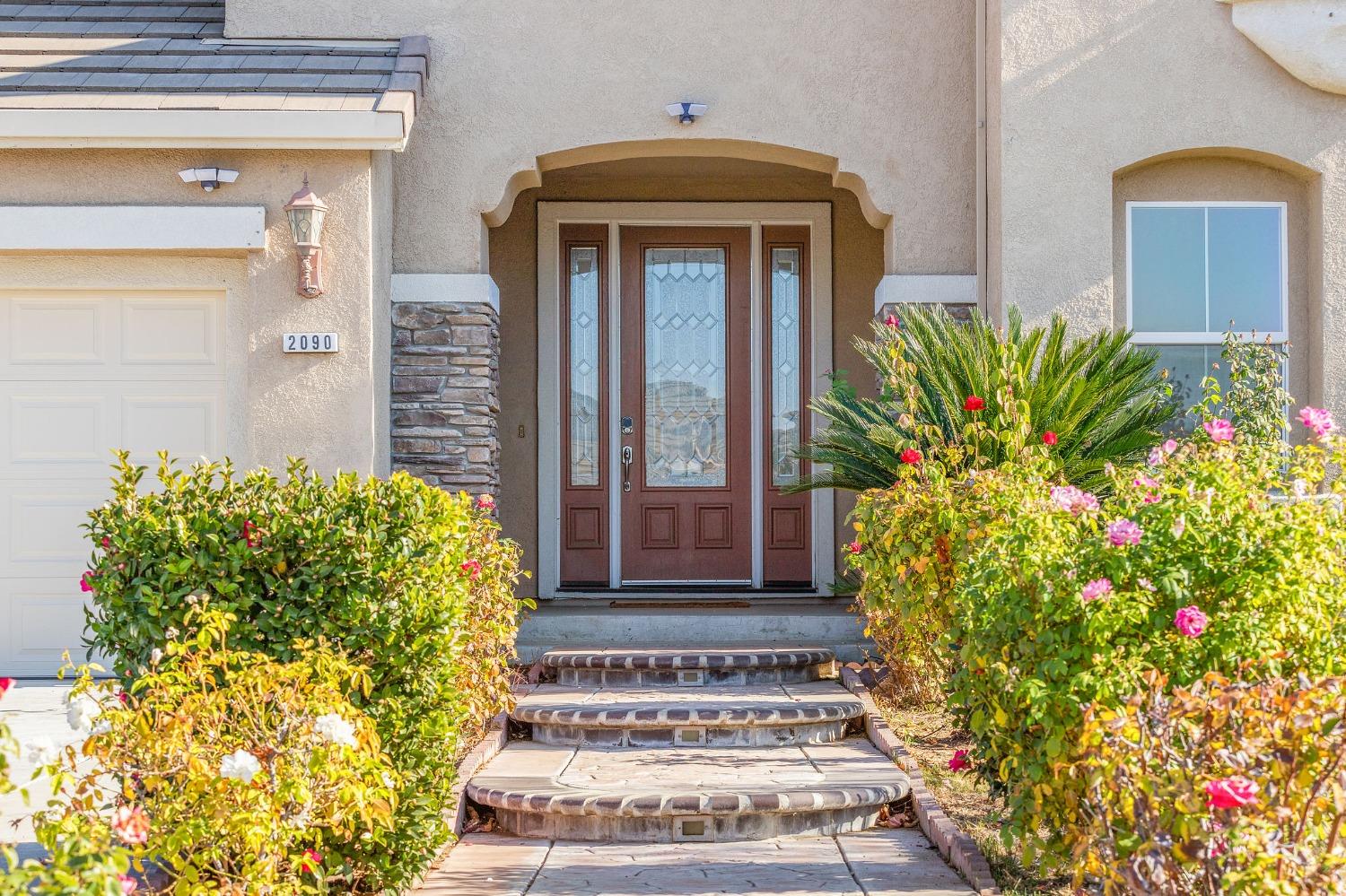 2090 Wisteria Place Manteca, CA 95337 - Photo 6 of 78 a front view of a house with lots of flowers