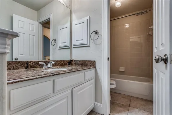 a bathroom with a granite countertop sink a mirror and a bathtub