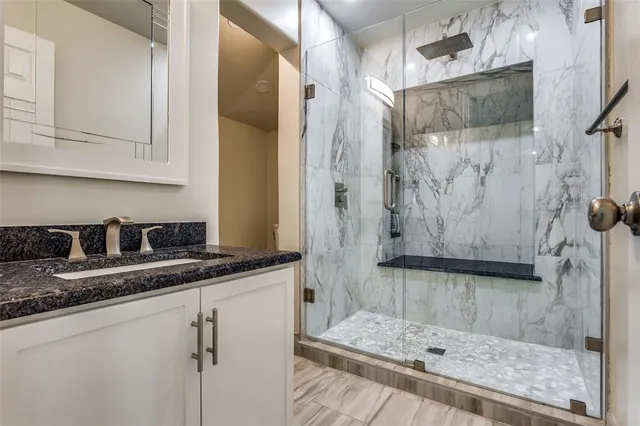 a bathroom with a granite countertop sink a mirror and shower