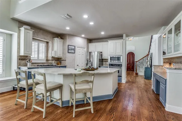 a kitchen with kitchen island granite countertop wooden floors and stainless steel appliances