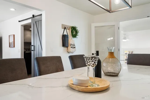 a dining room with chandelier fan and wooden floor