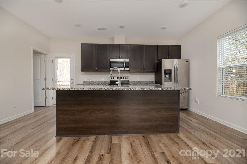5027 Elizabeth Road Charlotte, NC 28269 - Photo 7 of 23 a kitchen with kitchen island granite countertop a refrigerator and a sink