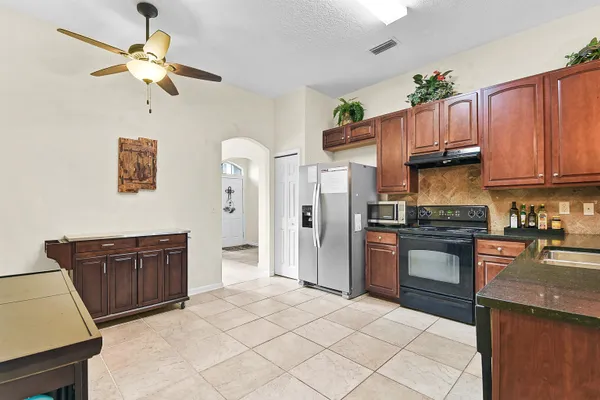 a kitchen with stainless steel appliances granite countertop a refrigerator a sink dishwasher stove and oven with wooden cabinets