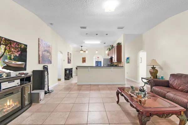 a living room with stainless steel appliances furniture a rug and a kitchen view