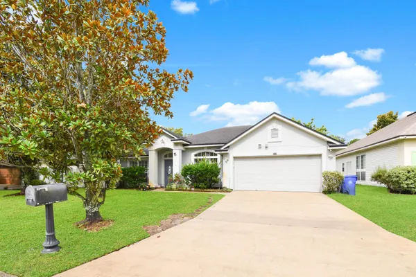 a front view of a house with a garden and trees