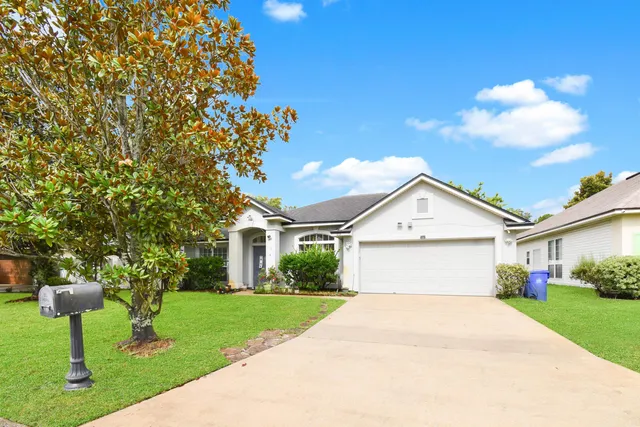 a front view of a house with a garden and trees