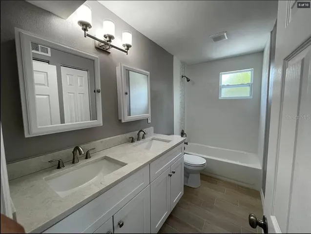 a bathroom with a granite countertop sink toilet and mirror
