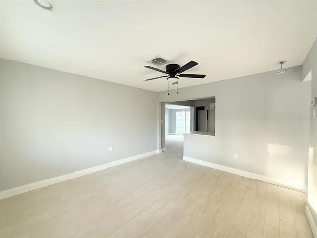 a view of a big room with a ceiling fan and windows