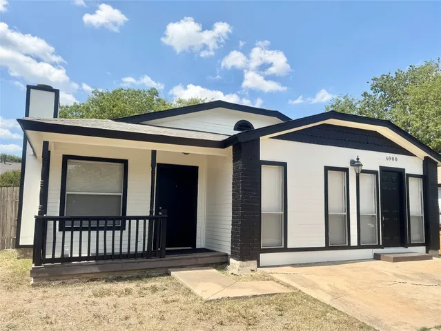 a view of a house with a small yard and wooden fence