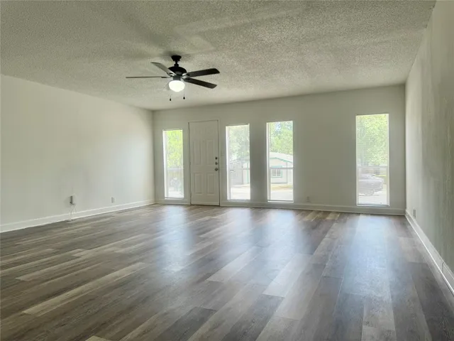 a view of an empty room with window and wooden floor