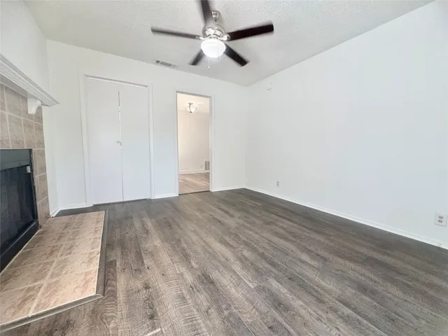 an empty room with wooden floor a ceiling fan and fireplace
