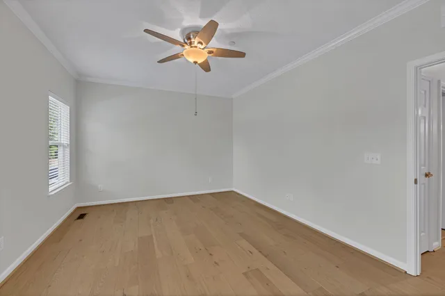 a view of an empty room with window and chandelier fan