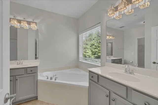 a bathroom with a granite countertop sink a bathtub and window
