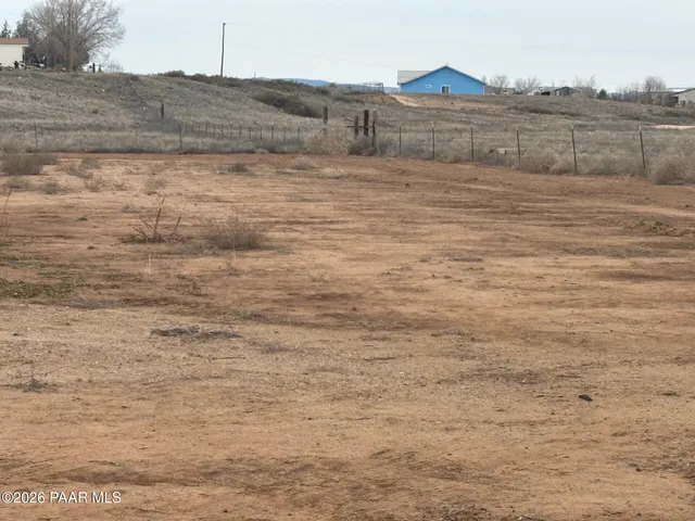 a view of a dry yard with wooden fence