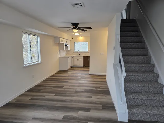 a view of a hallway to a house with wooden floor and a ceiling fan