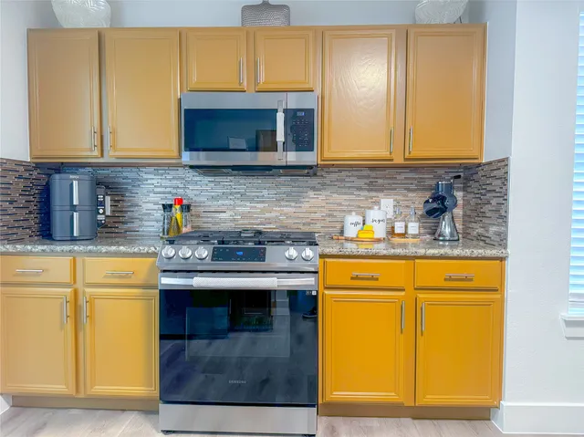 a kitchen with stainless steel appliances granite countertop wooden cabinets and a refrigerator
