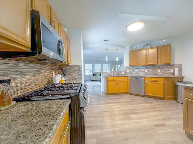 a kitchen with stainless steel appliances granite countertop a sink a stove counter space and cabinets