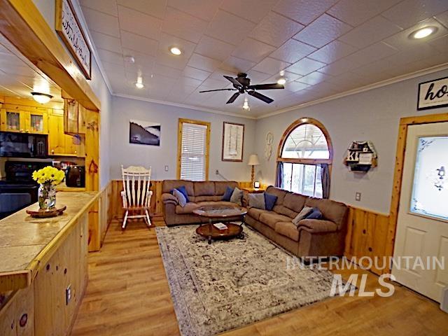 628 3rd Avenue South Payette, ID 83661 - Photo 4 of 19 Living area featuring a wainscoted wall, ceiling fan, wooden walls, light wood-style floors, and crown molding